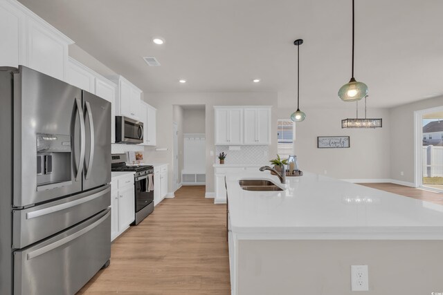 kitchen with appliances with stainless steel finishes, a sink, tasteful backsplash, light wood finished floors, and recessed lighting