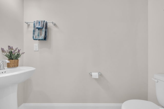 bathroom with toilet, a sink, and baseboards