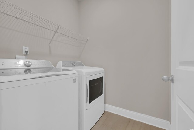 clothes washing area featuring washing machine and dryer and baseboards