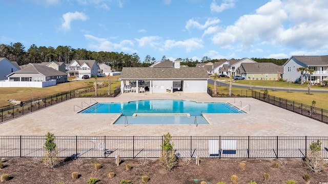 community pool with a residential view, a patio area, and fence