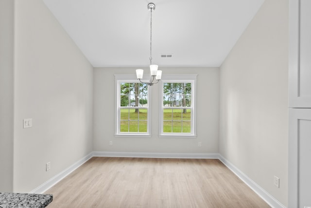 unfurnished dining area featuring a chandelier, light wood-type flooring, and baseboards