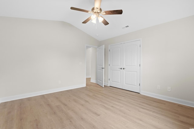 unfurnished bedroom with lofted ceiling, light wood-style flooring, a closet, baseboards, and ceiling fan
