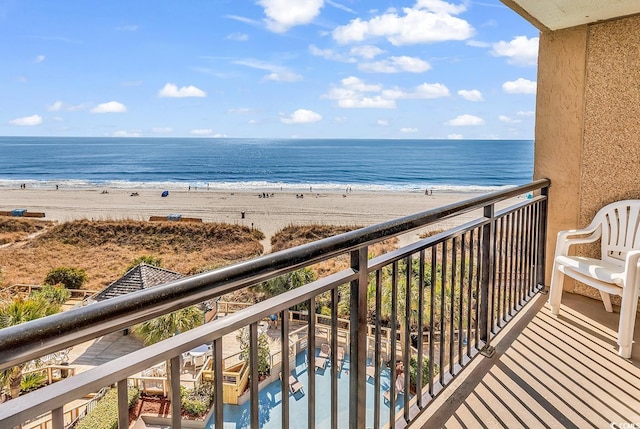 balcony with a water view and a view of the beach
