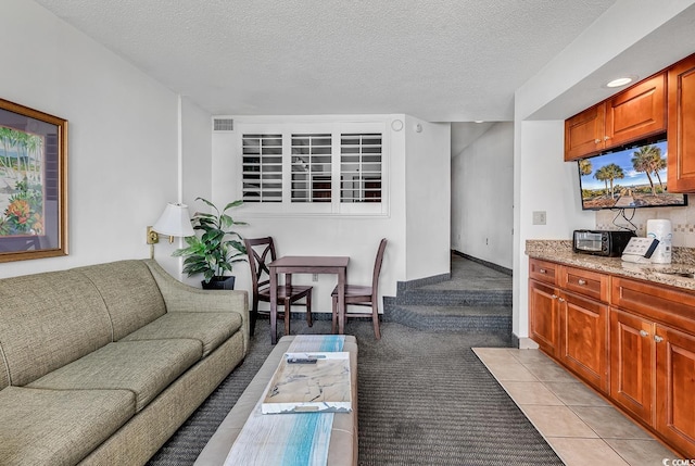 living area featuring light tile patterned floors, light colored carpet, a textured ceiling, and visible vents