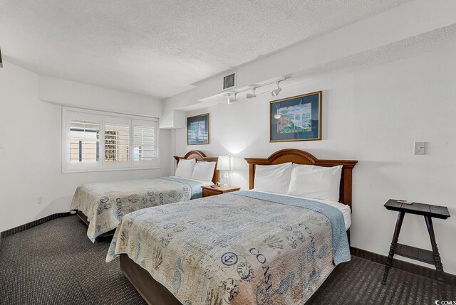 carpeted bedroom with visible vents, rail lighting, a textured ceiling, and baseboards
