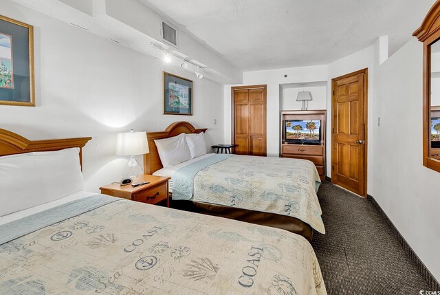 carpeted bedroom with rail lighting, visible vents, and a textured ceiling