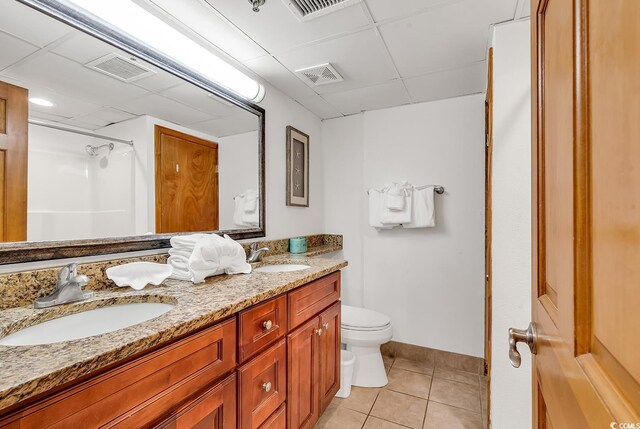bathroom featuring tile patterned floors, toilet, walk in shower, and a sink