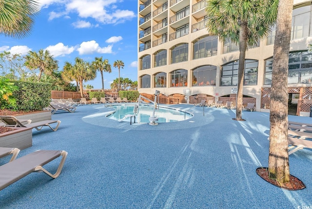 community pool with a patio and fence