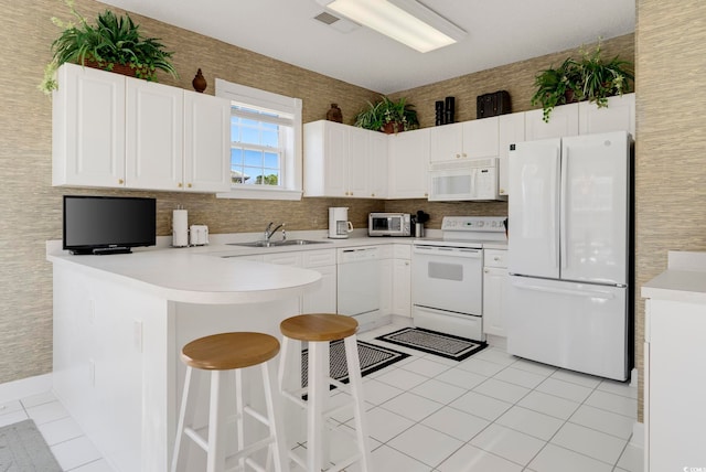 kitchen with white appliances, a sink, a peninsula, and light tile patterned flooring