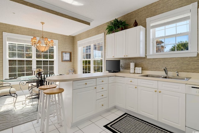 kitchen featuring a sink, dishwasher, a peninsula, a chandelier, and plenty of natural light