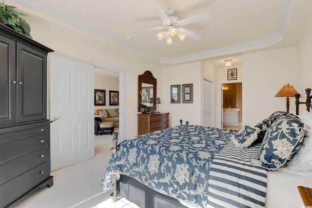 carpeted bedroom with crown molding, a ceiling fan, ensuite bathroom, and a raised ceiling