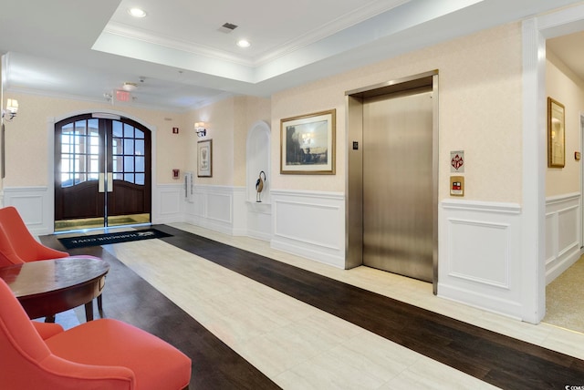 entryway featuring elevator, arched walkways, crown molding, wood finished floors, and a decorative wall