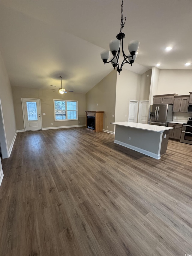 unfurnished living room featuring dark wood finished floors, baseboards, ceiling fan with notable chandelier, and lofted ceiling