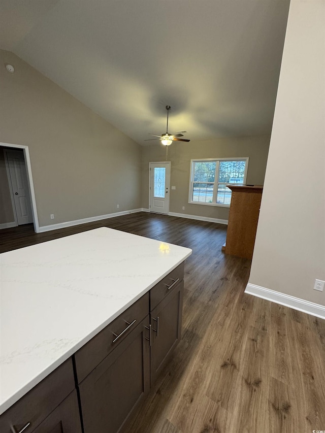 kitchen featuring dark wood-style flooring, ceiling fan, baseboards, vaulted ceiling, and light countertops