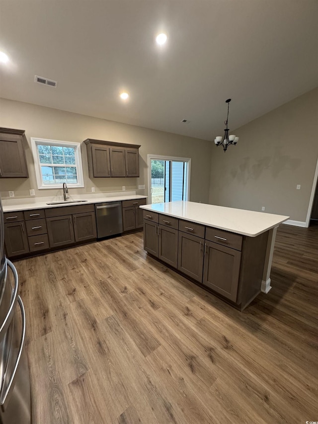 kitchen with a center island, dishwasher, wood finished floors, and visible vents