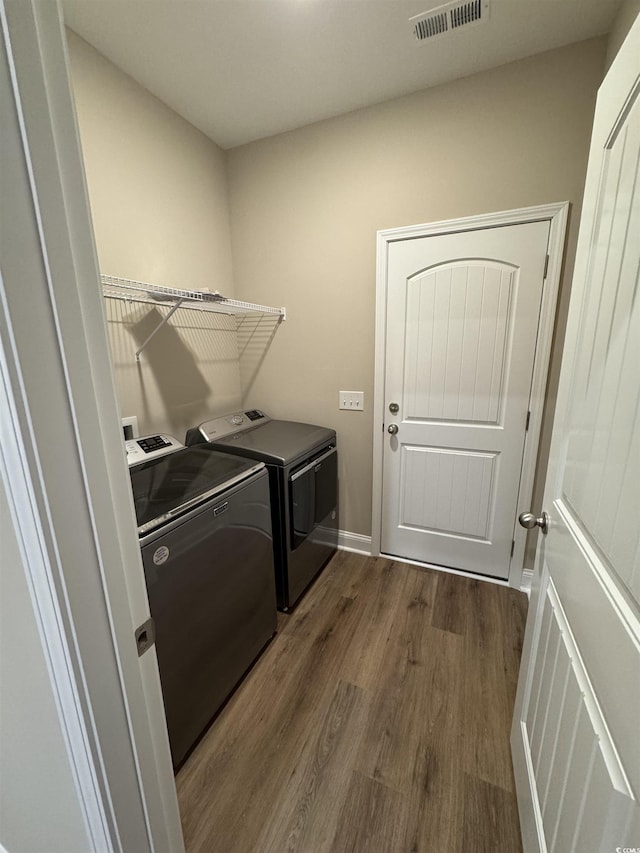 clothes washing area with separate washer and dryer, laundry area, dark wood-style flooring, baseboards, and visible vents