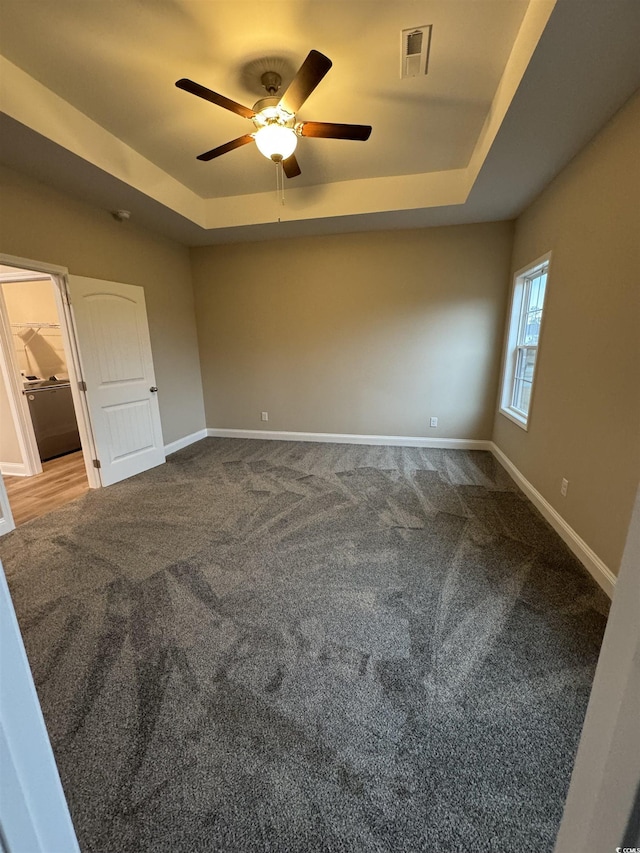 carpeted empty room with baseboards, visible vents, ceiling fan, and a tray ceiling