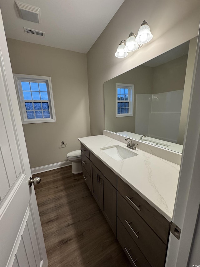 bathroom with visible vents, baseboards, toilet, wood finished floors, and vanity