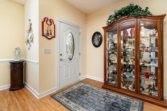 foyer entrance featuring light wood finished floors, visible vents, and baseboards