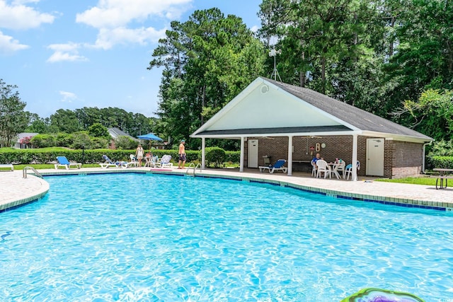 pool with a patio area and an outbuilding