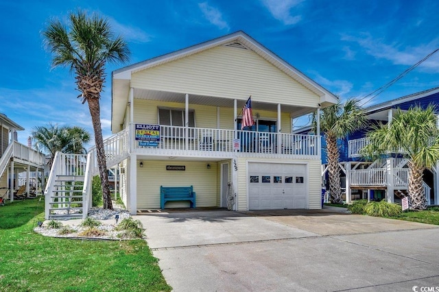 raised beach house featuring a porch, a garage, stairway, and concrete driveway