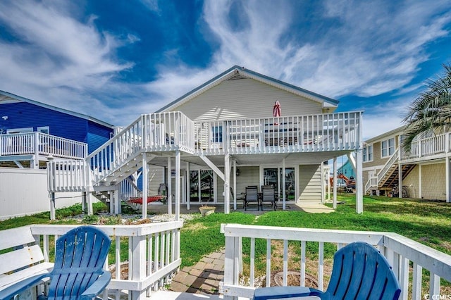 back of property with a yard, a wooden deck, stairs, and a patio area