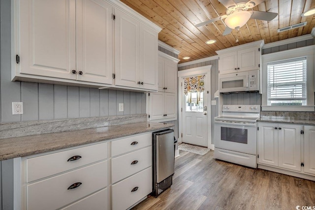 kitchen with white appliances, white cabinets, wooden ceiling, and a wealth of natural light