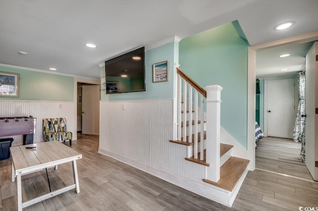 interior space featuring ornamental molding, wainscoting, stairs, and wood finished floors