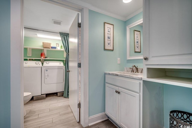 bathroom with visible vents, crown molding, vanity, wood finished floors, and washer and dryer