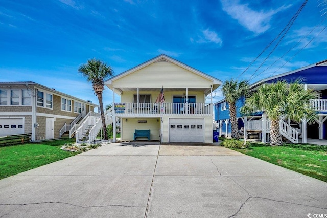 coastal inspired home featuring stairs, an attached garage, covered porch, and a front yard