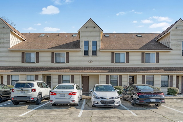 exterior space featuring uncovered parking and a shingled roof