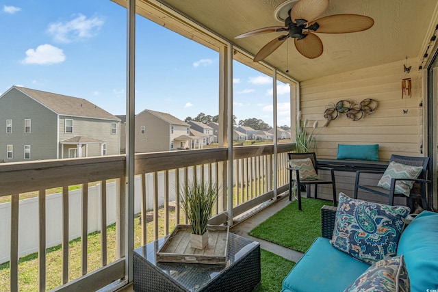 sunroom with a ceiling fan and a residential view