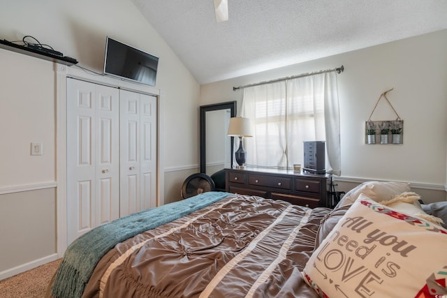 bedroom with a textured ceiling, a closet, carpet floors, lofted ceiling, and ceiling fan