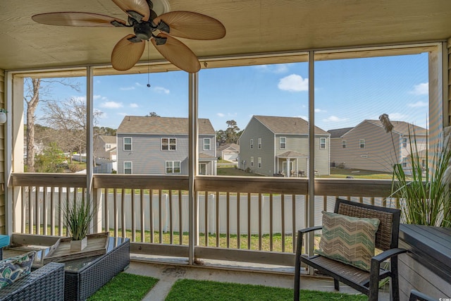 sunroom with a residential view and ceiling fan