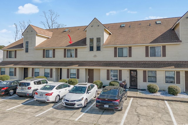 multi unit property with roof with shingles and uncovered parking