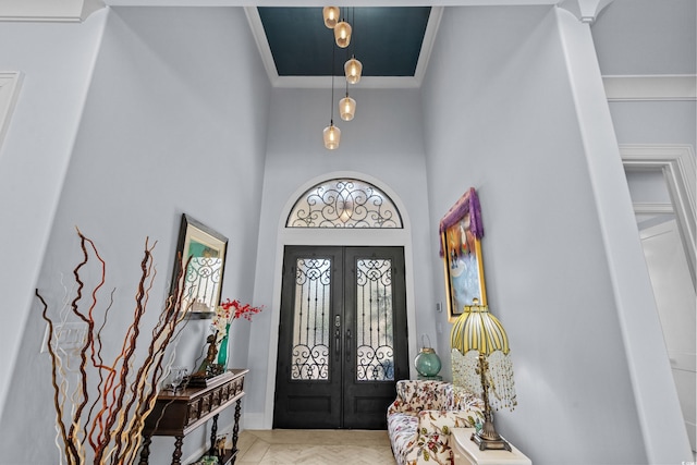 foyer entrance with a towering ceiling, french doors, and crown molding