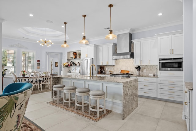 kitchen featuring backsplash, white cabinets, wall chimney exhaust hood, appliances with stainless steel finishes, and a sink