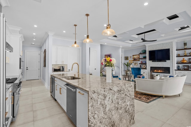 kitchen featuring white cabinets, a sink, ornamental molding, a spacious island, and a large fireplace