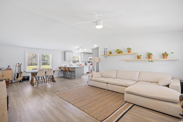living room featuring a ceiling fan, lofted ceiling, and light wood-style floors