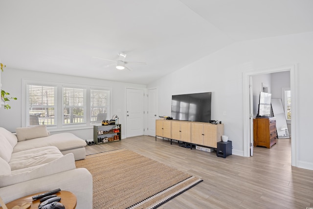 living area with lofted ceiling, light wood-style floors, baseboards, and ceiling fan