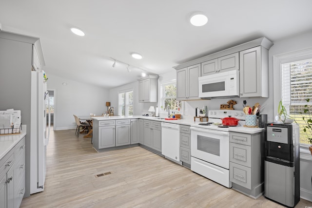 kitchen with white appliances, a healthy amount of sunlight, visible vents, a peninsula, and gray cabinets