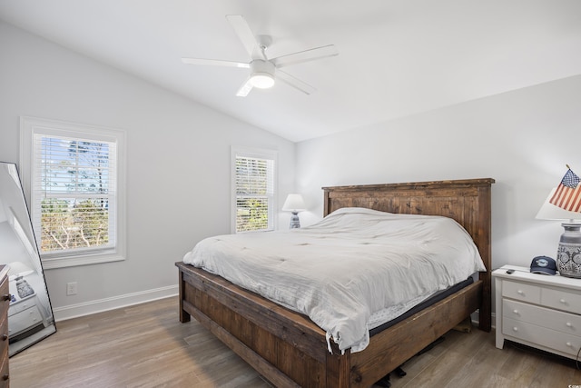 bedroom with ceiling fan, baseboards, light wood-type flooring, and lofted ceiling