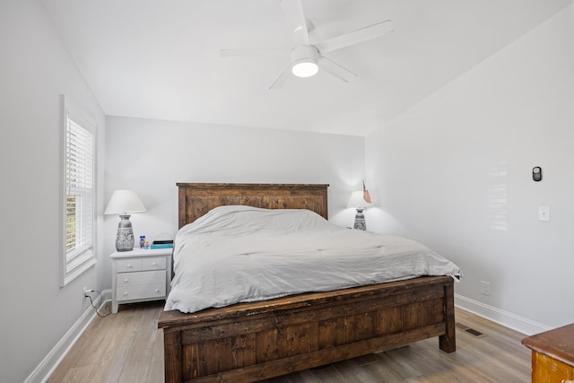bedroom featuring visible vents, baseboards, lofted ceiling, and light wood-style floors