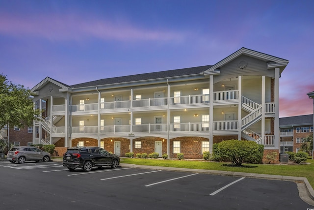 3927 Gladiola Ct Unit 101, Myrtle Beach, SC 29588 - property at dusk featuring uncovered parking, stairs, and central AC