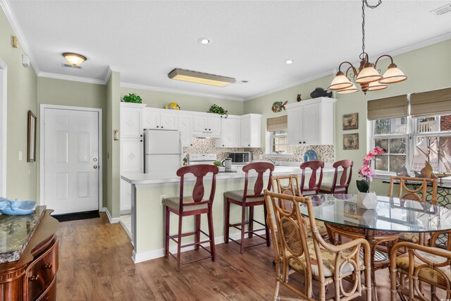 3927 Gladiola Ct Unit 101, Myrtle Beach, SC 29588 - dining area featuring dark wood finished floors, ornamental molding, a chandelier, and recessed lighting
