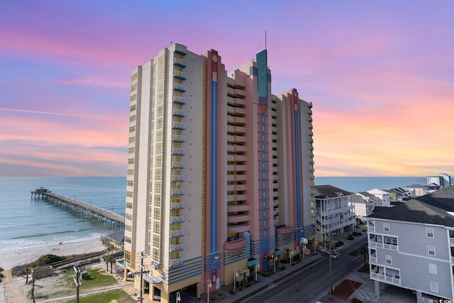 property at dusk with a beach view and a water view