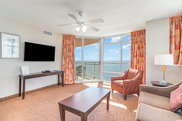 living area with a wall of windows, carpet, baseboards, visible vents, and ceiling fan