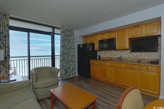 kitchen with dark wood finished floors, a water view, decorative backsplash, and black appliances