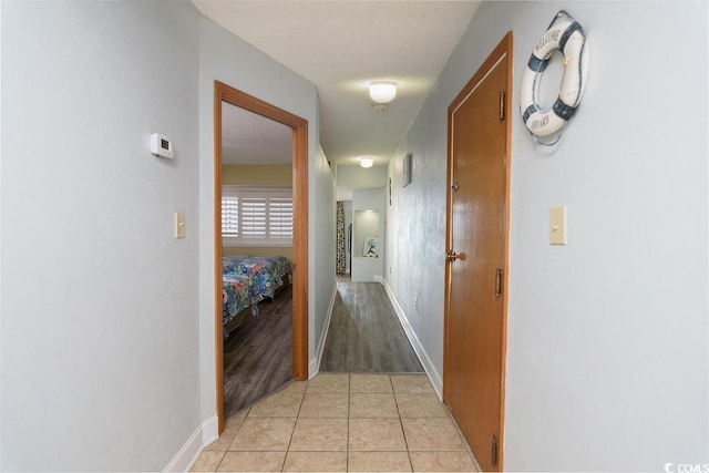 hall featuring light tile patterned floors and baseboards
