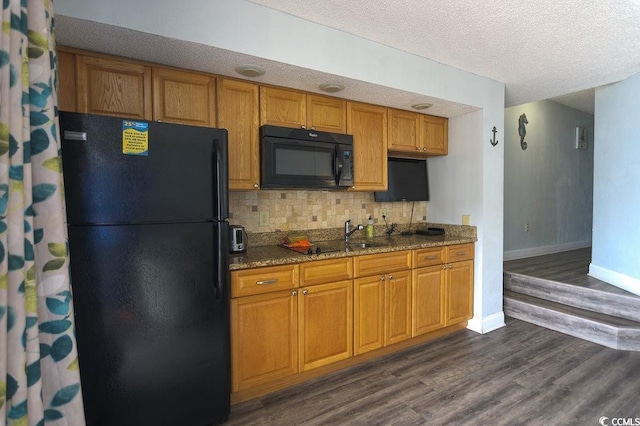 kitchen with stone counters, brown cabinets, dark wood-style flooring, black appliances, and decorative backsplash